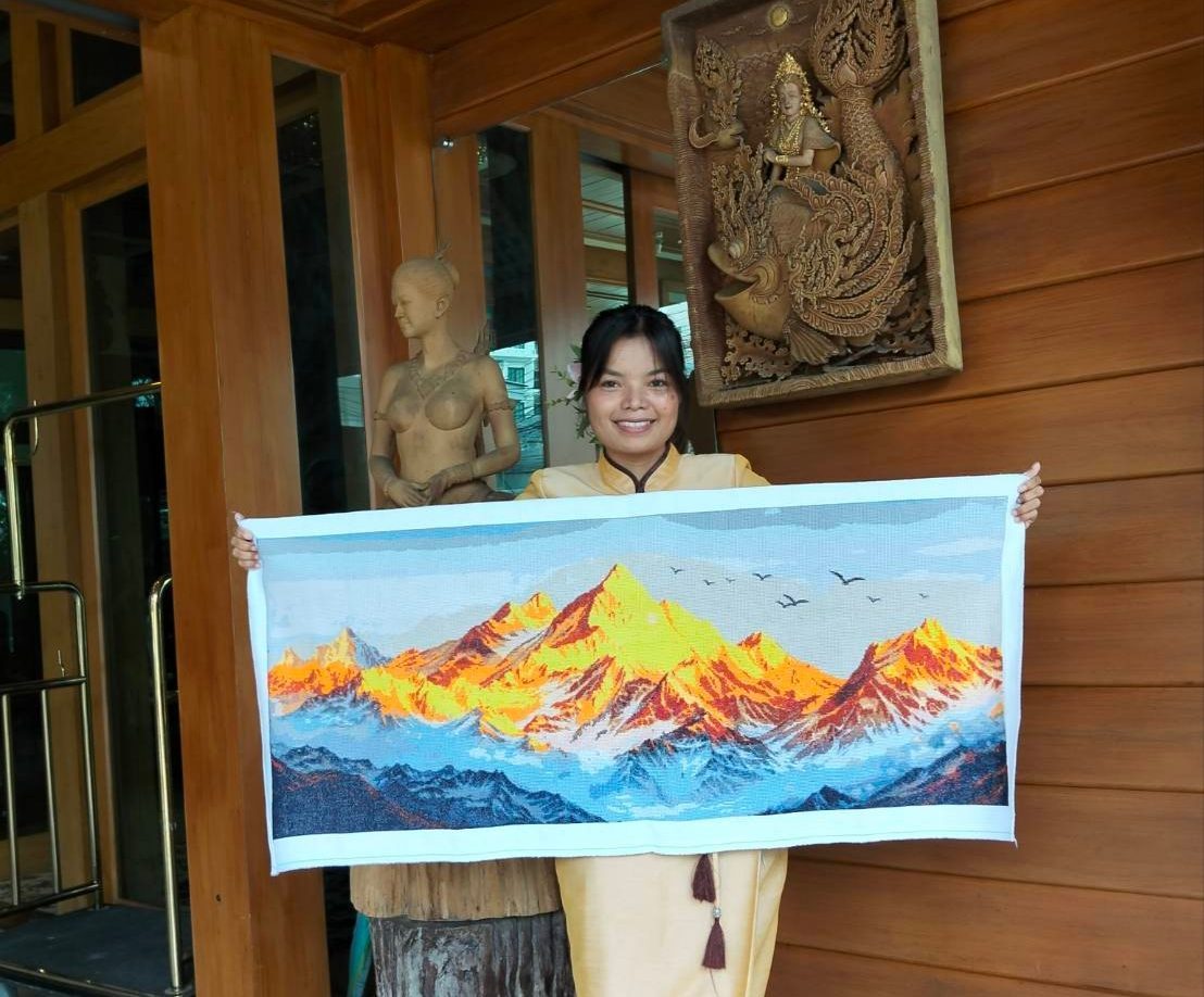 Sassy's finished mountain landscape cross stitch, held up at home